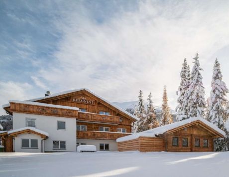 Eine gemütliche Berghütte mit Holzverkleidung, umgeben von verschneiten Bäumen und Bergen